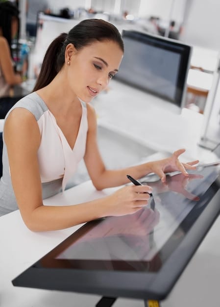 A fashion designer in a Spanish studio using an AI-powered software on a large touchscreen display to create a dress design. Several fabric swatches and design sketches are scattered around the workspace.
