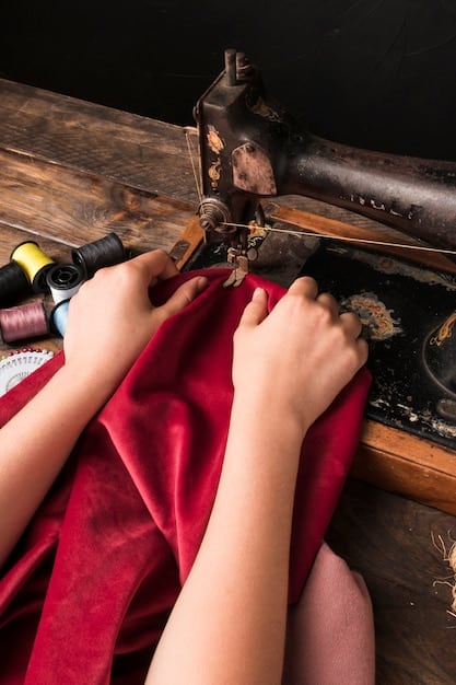 A close-up shot of hands sewing a garment in a small, brightly lit artisan workshop in Spain. The focus is on the skilled craftsmanship and attention to detail. Natural light pours through a window, highlighting the texture of the sustainable fabric being used.