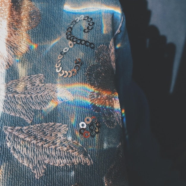 A detailed close-up shot of a collaborative fashion piece combining traditional Spanish embroidery techniques with modern, minimalist design elements.