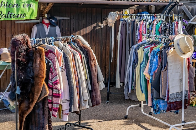 A brightly lit, well-organized thrift store in Spain. Racks of clothing in various styles and colors are neatly displayed. Shoppers are browsing through the selections, examining the garments. The store has a clean, modern aesthetic with signage indicating different sections (e.g., women's, men's, children's).
