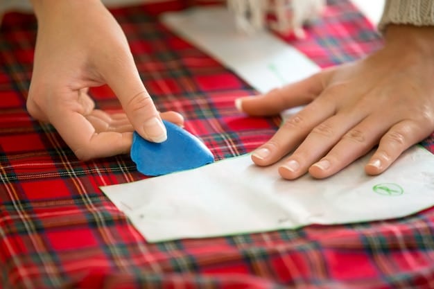 A close-up shot of hands carefully mending a torn seam on a piece of clothing in a well-lit workshop. Sewing tools and a variety of fabric scraps are visible in the background. The focus is on the precision and care taken during the repair process, emphasizing the value of clothing repair and maintenance.