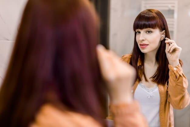 A woman choosing between different earrings (hoops, studs, dangling) in front of a mirror, highlighting how the right earrings can complement her facial features and overall style.