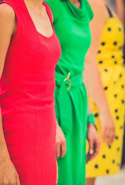 A close-up of colorful neon clothing options, including pink, green, and yellow tops and dresses, arranged against a brightly lit studio backdrop.