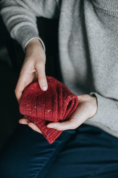 A close-up shot of a woman's hands holding a high-quality navy blue cashmere sweater, showcasing the texture and material of a timeless garment.