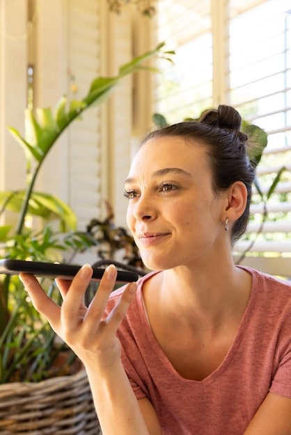 A Spanish influencer applying a moisturizing cream to her face with gentle, upward strokes in a brightly lit bathroom.