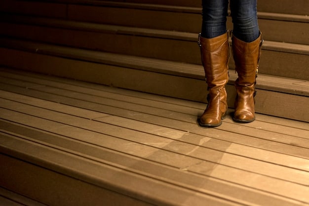 A pair of freshly polished brown leather boots sitting on a wooden surface. The boots are gleaming, almost mirroring the light, and show no signs of wear or scratches.