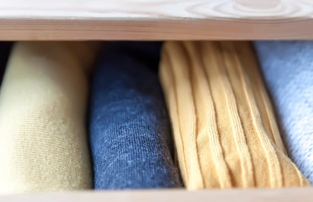 A close-up of a section of the closet focusing on different textures. There are soft knit sweaters, smooth silk blouses, and structured denim jeans. Each texture is neatly folded or hung together, showcasing the variety.