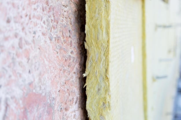 A close-up of a worker installing energy-efficient insulation material in the wall of a house. The insulation is bright yellow and fills the cavity completely.