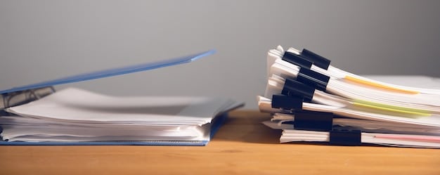 A close-up shot of official documents related to unemployment benefits. The documents are spread out on a wooden table, with a pen resting on top of one of them. The focus is on the word 