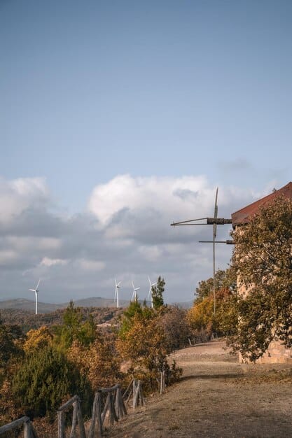 Image of a wind farm in Spain with solar panels in the background, illustrating the country's commitment to renewable energy and the ecological transition.