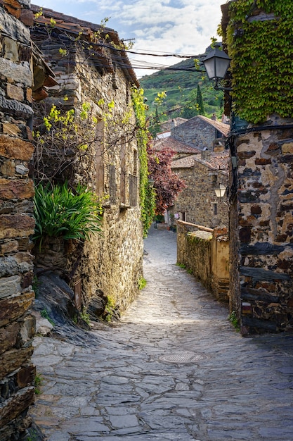 A scenic vista of a traditional Spanish village nestled in the mountains, showcasing cobblestone streets, historic buildings, and lush green landscapes. The image should evoke a sense of tranquility, cultural richness, and the appeal of rural tourism.