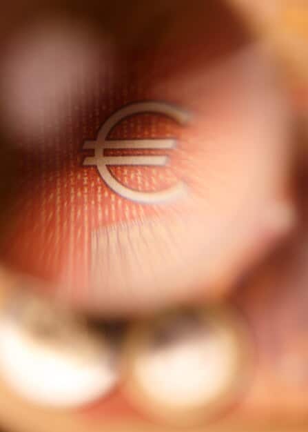 A close-up shot of a Spanish Euro coin, showing the intricate details, surrounded by blurred charts and graphs in the background. The focus should be on the coin, symbolizing financial stability.