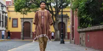 Mujer luciendo un sarape moderno de diseñador mexicano en una calle vibrante de la Ciudad de México, combinando tradición y vanguardia en su atuendo.