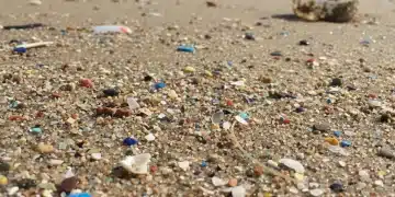 Nahaufnahme von Mikroplastikpartikeln im Sand, Symbol für die Umweltverschmutzung.