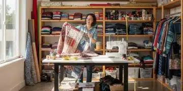 Kreative Person beim Upcycling von Mode zu Hause, umgeben von Stoffen und Nähutensilien.