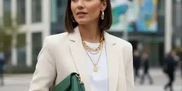 Mulher estilosa com blazer creme, colar dourado e bolsa vibrante, mostrando as tendências de acessórios 2026.